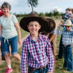 Kid smiling at camera with wide brim hat rural health charity